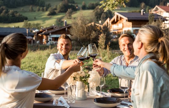 Freunde genießen zusammen ein Abendessen im Alpzitt Chalet im Dorf in Burgberg