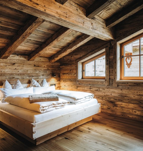 Einbick in eines der Schlafzimmer im Alpzitt Chalet im Dorf in Burgberg mit Blick auf ein gemütliches Doppelbett