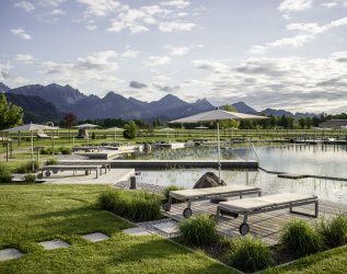 Einblick in den großen Außenbereich des Hotel König Ludwigs in Schwangau mit Liegen direkt am Wasser