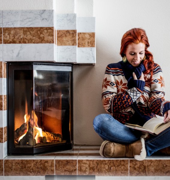 Eine Frau liest am Kamin im Das Freiberg Romantik Hotel in Oberstdorf ein Buch