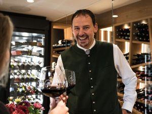 Ein Mitarbeiter im Bergkristall - Mein Resort im Allgäu in Oberstaufen stößt mit einer anderen Person mit einem Weinglas an