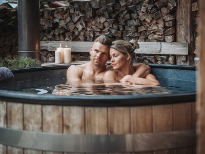 Ein Paar genießt ein Bad im Badezuber in einem der Alpzitt Chalets im Dorf in Burgberg