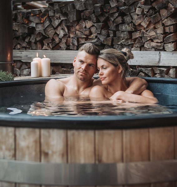 Ein Paar genießt ein Bad im Badezuber in einem der Alpzitt Chalets im Dorf in Burgberg