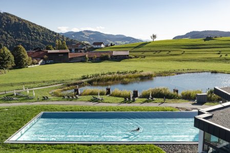 Außenansicht vom Wellnessbereich mit Naturbadesee und Außenpool im Haubers Naturresort in Oberstaufen