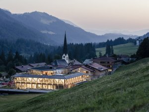 Außenansicht vom HUBERTUS Mountain Refugio Allgäu in Balderschwang am Abend mit Blick auf den hell erleuchteten SPA-Bereich