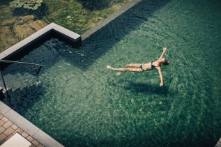 Eine Frau schwimmt im Außenpool vom Hotel Torghele's Wald & Fluh in Balderschwang