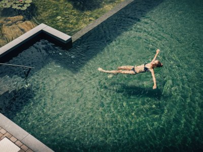 Eine Frau schwimmt im Außenpool vom Hotel Torghele's Wald & Fluh in Balderschwang
