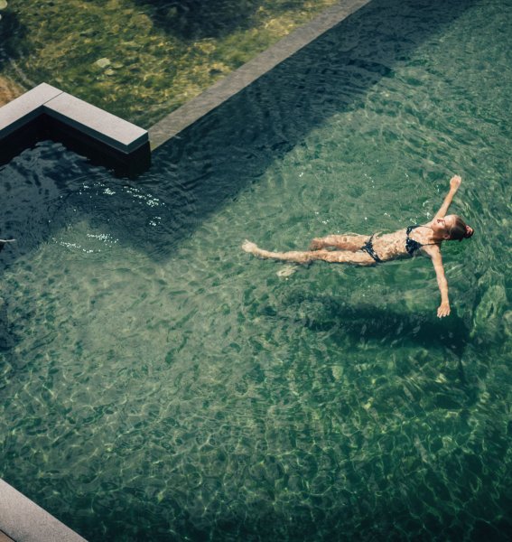 Eine Frau schwimmt im Außenpool vom Hotel Torghele's Wald & Fluh in Balderschwang