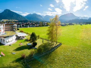 Außenansicht vom Hotel Alpenhof im Sommer mit Blick auf die grüne Natur in Oberstdorf