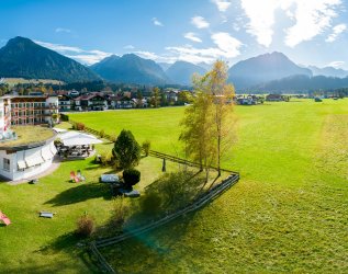 Außenansicht vom Hotel Alpenhof im Sommer mit Blick auf die grüne Natur in Oberstdorf