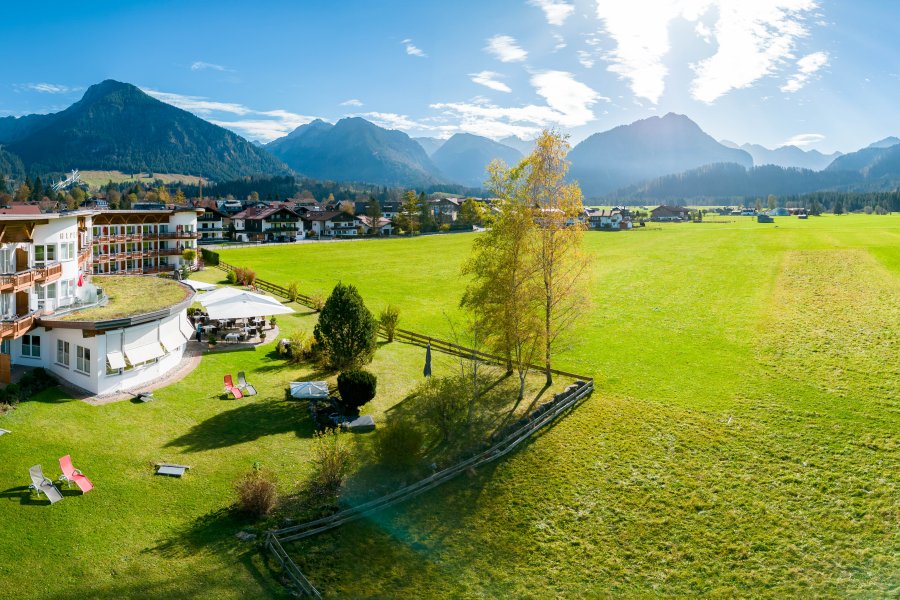 Außenansicht vom Hotel Alpenhof im Sommer mit Blick auf die grüne Natur in Oberstdorf