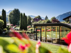 Sommerliche Blick in den blühenden Garten des Hotel Franks und im Hintergrund Berge.