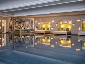 Wellnessbereich mit drei Doppelbetten und Wohlfühlecke. Blick auf den innen Pool.