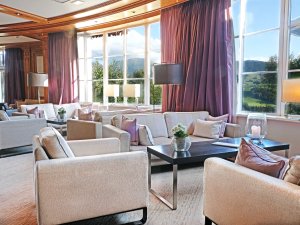 Gemütliche Lounge mit grauen Sesseln und Blick auf die grünen Berge und Wiesen in Oberstaufen.