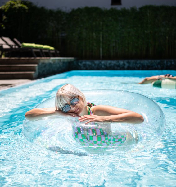 Gäste genießen den Sommer im Außenpool vom Freiberg Romantik Hotel in Oberstdorf