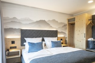 Einblick in eines der Chalet-Appartement im Mondi Resort Oberstaufen mit Blick auf ein großes Doppelbett und moderner Ausstattung