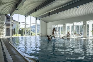 Eine Familie planscht zusammen im Mondi Resort Oberstaufen Innenpool
