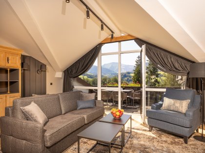 Einblick in eines der Familien Appartements im Mondi Resort in Oberstaufen mit Blick auf ein gemütliches Sofa und den Balkon mit tollem Ausblick