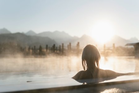 Ein Gast genießt die Auszeit im Hotel König Ludwig in Schwangau im großen Außenpool des Hotels