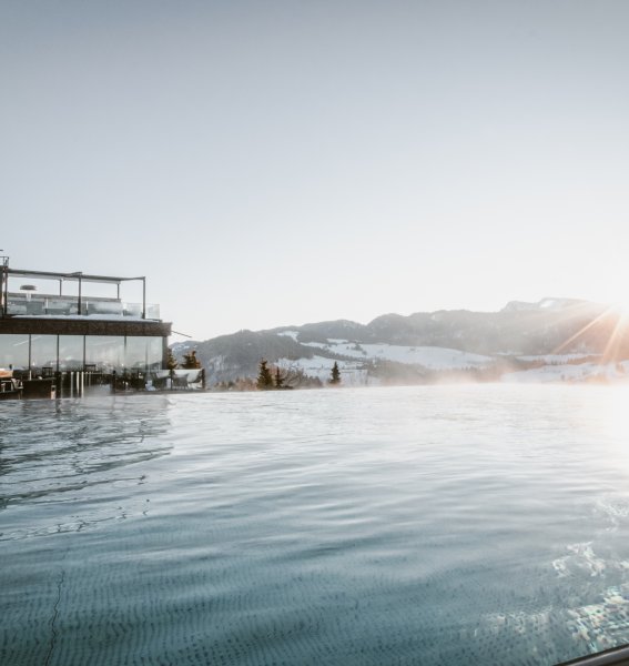 Blick auf den Infinitypool und die verschneite Umgebung im Bergkristall - Mein Resort im Allgäu in Oberstaufen