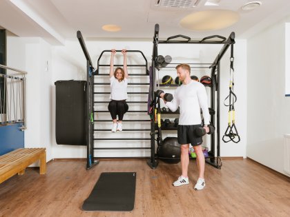 Zwei Gäste trainieren im gut ausgestatteten Fitnessraum im Mondi Resort in Oberstaufen