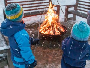 Zwei Kinder stehen vor einem Lagerfeuer im MONDI Resort in Oberstaufen