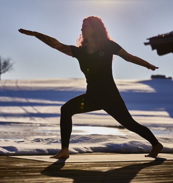 Eine Frau macht im Außenbereich des Haubers Naturresort in Oberstaufen im Winter eine Yoga Übung