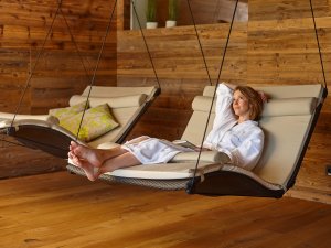 Eine Frau genießt eine Auszeit auf einer Ruheliege im Wellnessbereich des Biohotel Eggensberger in Füssen / Hopfen am See