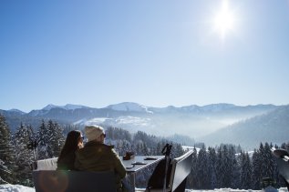 Zwei Gäste blicken in die verschneite Landschaft rund um das Haubers Naturresort in Oberstaufen