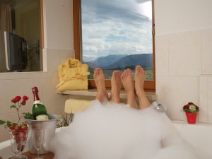 Ein Paar genießt Zweisamkeit in der großen Badewanne in eines der Zimmer im Landhotel Alphorn in Ofterschwang
