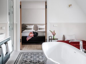 Einblick in eines der Zimmer im AMERON Neuschwanstein Hotels in Schwangau mit Blick auf eine freistehende Badewanne