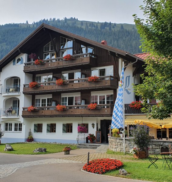 Außenansicht des Hotelgebäudes des Alpengasthofs Löwen in Oberjoch im Sommer vor Bergpanorama