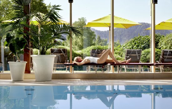 Ein Gast entspannt am Innenpool im Hotel Sommer in Füssen und genießt die Sonne