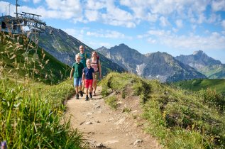 Es ist eine Familie zu sehen, die einen Wanderausflug in den Bergen machen.