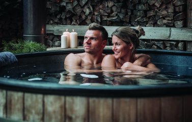 Paar im Pool des Spa-Chalets im Kerzenlicht.