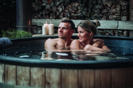 Paar im Pool des Spa-Chalets im Kerzenlicht.