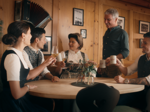 Ansicht der Gastgeber-Familie, die in gemeinsam an einem Tisch des Hotel Bergkristall in Oberstaufen sitzen und mit den Gläsern anstoßen.