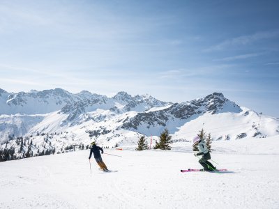 Es sind zwei Leute zu sehen, die in der Umgebung von Oberstdorf bei schönem Wetter Skifahren sind.