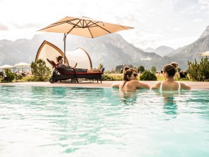 Gäste genießen die Auszeit im Außenpool im Hotel Rübezahl in Schwangau.