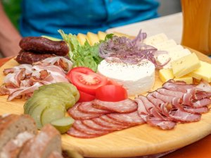 Es ist eine Brotzeitplatte des Bio-Berghotels Ifenblick in Balderschwang zu sehen, auf welcher Salami, Schinken, Käse und Gemüse angerichtet ist.