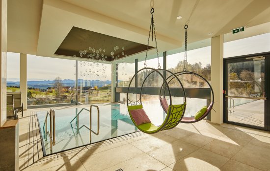 Es ist der Innenpool und zwei besondere Liegen im Hotel Edita in Scheidegg im Sommer zu sehen.