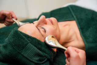 Es ist eine Frau in grünen Handtücher gewickelt zu sehen, welche gerade eine Kosmetik-Behandlung im Hotel Allgäu Sonne in Oberstaufen genießt.