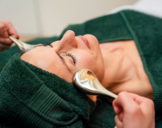 Es ist eine Frau in grünen Handtücher gewickelt zu sehen, welche gerade eine Kosmetik-Behandlung im Hotel Allgäu Sonne in Oberstaufen genießt.