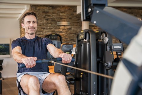 Es ist ein Mann zu sehen, der gerade im Fitnessraum des Hotel Allgäu Sonne in Oberstaufen Übungen macht.