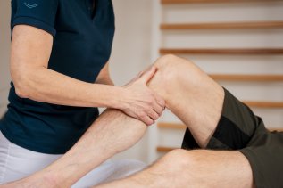 Es sind zwei Beine zu sehen eines Mannes, der auf einer Behandlungsliege des Hotels Allgäu Sonne in Oberstaufen liegt und von einem zweiten Mann an den Beinen behandelt wird.