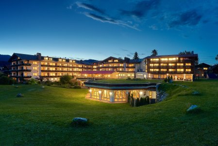 Es ist die beleuchtende Außenansicht des SCHÜLE'S Gesundheitsresort und SPA in Oberstdorf zu sehen.