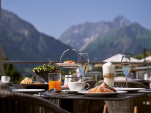 Es ist ein Tisch mit Frühstück darauf zu sehen auf der Terrasse des Travel Charme Ifen Hotel im Kleinwalsertal