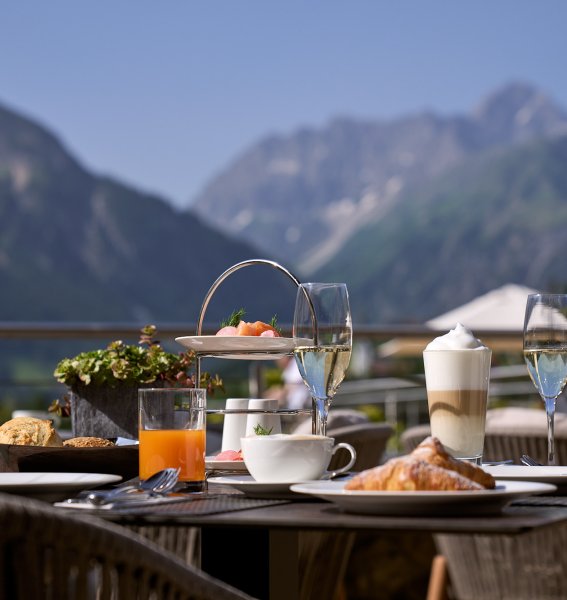 Es ist ein Tisch mit Frühstück darauf zu sehen auf der Terrasse des Travel Charme Ifen Hotel im Kleinwalsertal
