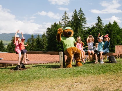 Es sind Kinder und ein Maskottchen auf dem Sommerfest des Mondi Resort Oberstaufen im Sommer zu sehen.