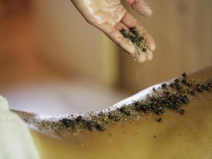 Es ist zu sehen, wie eine Frau eine Massage in Form eines Salzpeelings im HUBERTUS Mountain Refugio in Balderschwang genießt